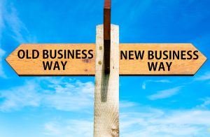 Wooden signpost with two opposite arrows over clear blue sky Old Business Way and New Business Way Business change conceptual image