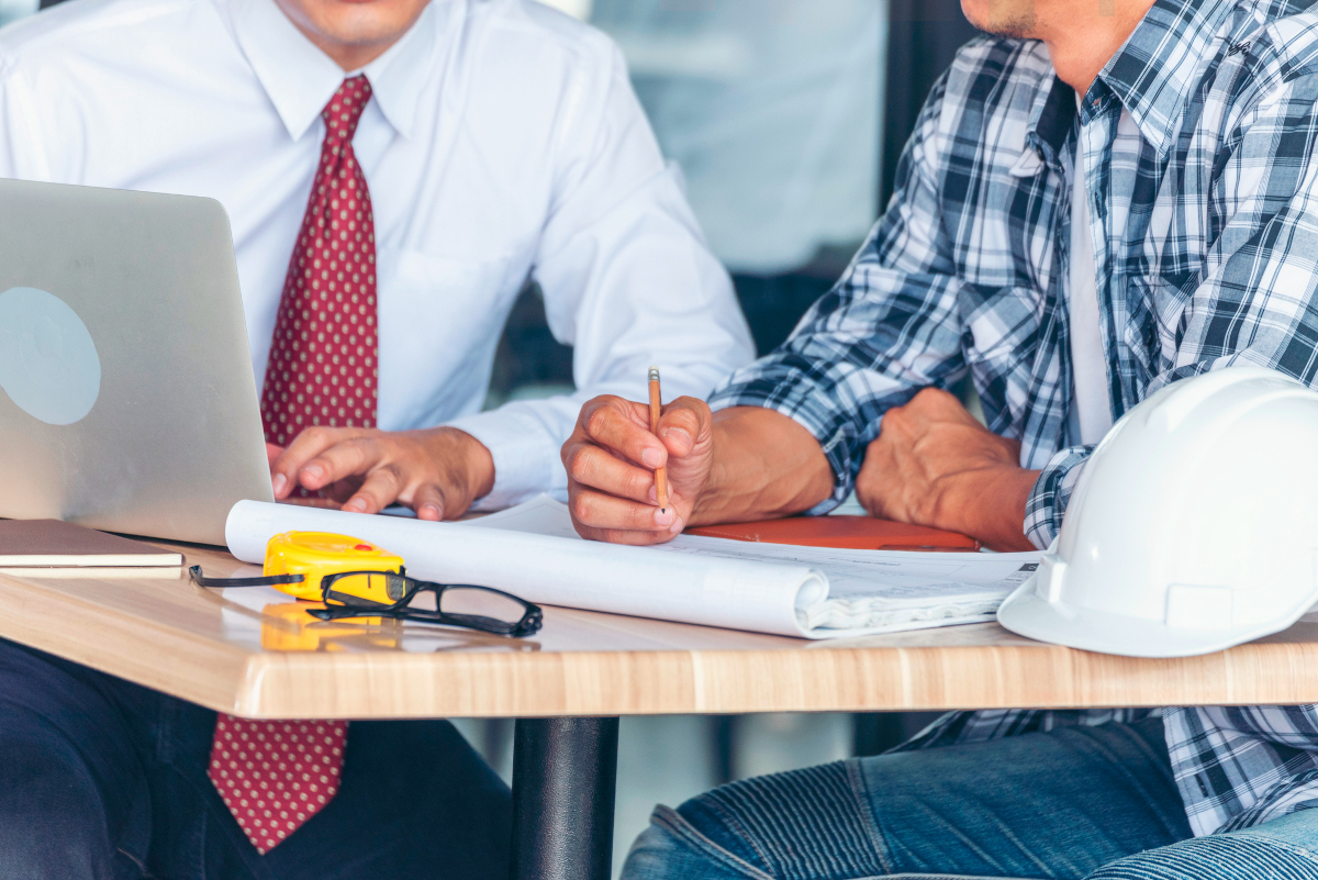 Contractor construction engineer meeting together on architect table at construction site. Business man and engineer manager discussing with foreman team builder blueprint planning design paperwork.